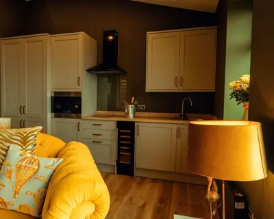 a kitchen with white cabinets and a yellow couch at The Wellsprings Lodges and Restaurant in Clitheroe