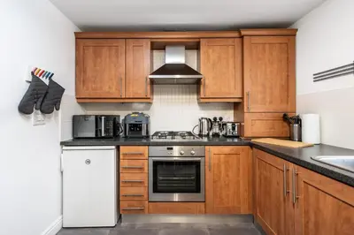 a kitchen with wooden cabinets and a stove top oven at The Point , 2 Bed, Parking - Pass the Keys in Knowsley