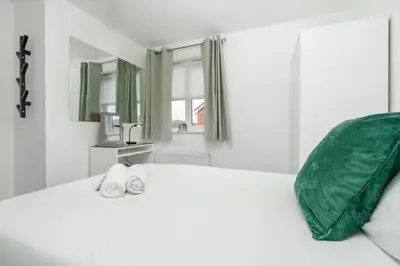 a white bed with a green pillow and a sink at The Point , 2 Bed, Parking - Pass the Keys in Knowsley