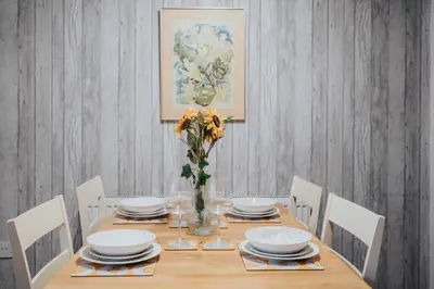 a dining room table with chairs and a vase of flowers at The Point , 2 Bed, Parking - Pass the Keys in Knowsley