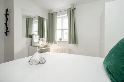 a white bed with a green pillow and towels on it at The Point , 2 Bed, Parking - Pass the Keys in Knowsley