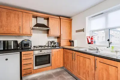 a kitchen with wooden cabinets and a sink at The Point , 2 Bed, Parking - Pass the Keys in Knowsley