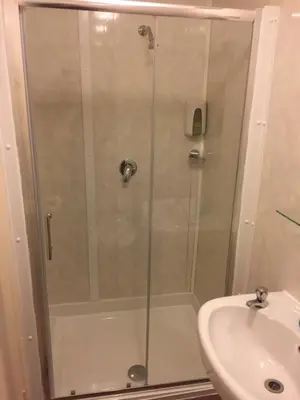 a shower with a glass door next to a sink at Chaplins in Blackpool