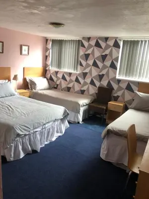 a hotel room with two beds and a chair at Chaplins in Blackpool