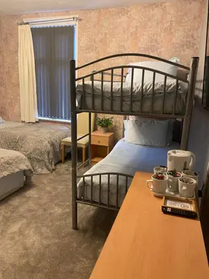 a bedroom with two bunk beds and a table at Chaplins in Blackpool