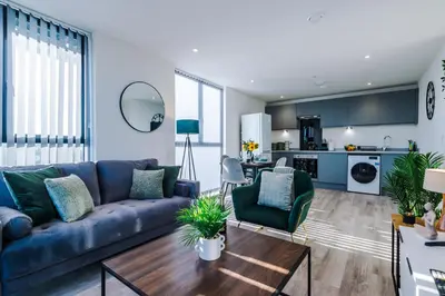 a living room with a blue couch and a kitchen at NEW! Stunning 2-bed apartment in Liverpool by 53 Degrees Property - Amazing location, Ideal for Small Groups - Sleeps 4! in Liverpool