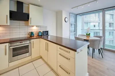 a kitchen with white cabinets and a table with chairs at Host & Stay - The Municipal View Abode in Liverpool