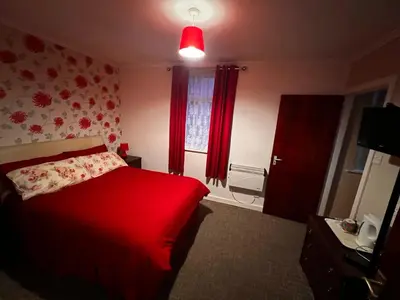 a bedroom with a red bed and a window at Lynton Hotel in Blackpool