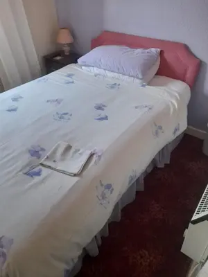 a bed with a white bedspread with blue flowers on it at Lynton Hotel in Blackpool