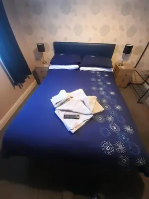 a bed with a blue comforter with two shirts on it at Lynton Hotel in Blackpool