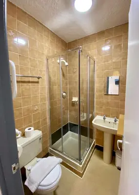 a bathroom with a shower and a toilet and a sink at Alumhurst Hotel in Blackpool