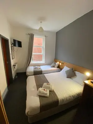 a hotel room with two beds and a window at Alumhurst Hotel in Blackpool