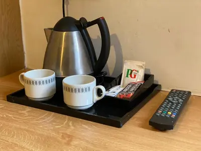 a tea kettle and two cups and a remote control at Alumhurst Hotel in Blackpool