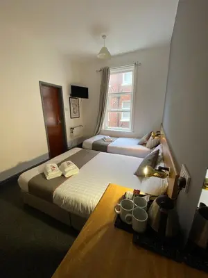 a hotel room with two beds and a table and a window at Alumhurst Hotel in Blackpool