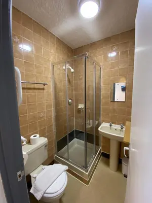 a bathroom with a shower and a toilet and a sink at Alumhurst Hotel in Blackpool