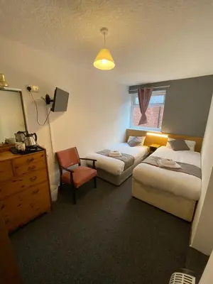 a hotel room with two beds and a mirror at Alumhurst Hotel in Blackpool