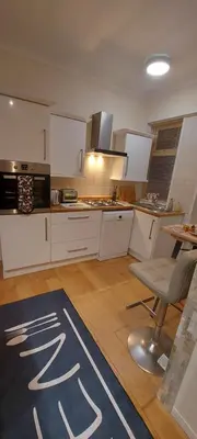 a kitchen with white cabinets and a table and chairs at OLIVE TREE - 2 Master bedroom (sleeps 6) in Blackpool