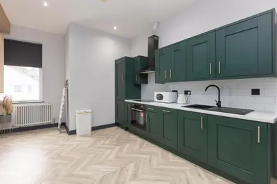 a kitchen with green cabinets and a wooden floor at Ettie and Gigi's in Blackpool