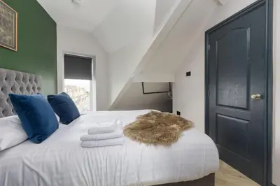 a bedroom with a white bed with blue pillows at Ettie and Gigi's in Blackpool