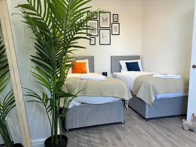 a bedroom with two beds and a potted plant at Now Screening…Large Movie Place 60 Inch TV (Sleep 11) in Liverpool