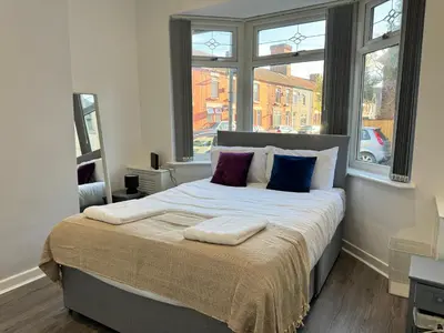 a bedroom with a large bed with two windows at Now Screening…Large Movie Place 60 Inch TV (Sleep 11) in Liverpool