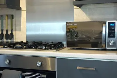 a kitchen counter with a stove and a microwave at 2 Bedroom City Centre Duplex Apt in Preston