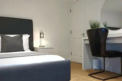 a bedroom with a bed and a black chair at 2 Bedroom City Centre Duplex Apt in Preston