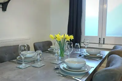 a table with plates and glasses and yellow flowers on it at 2 Bedroom City Centre Duplex Apt in Preston