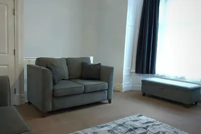a living room with a couch and a ottoman at 2 Bedroom City Centre Duplex Apt in Preston