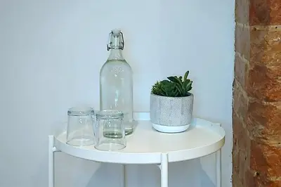 a bottle and glasses on a shelf with a plant at 2 Bedroom City Centre Duplex Apt in Preston