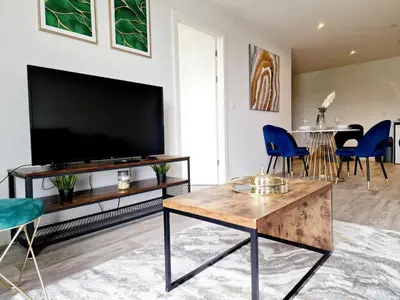 a living room with a large television and blue chairs at Westminster Luxury Liverpool Apartment with Free Parking in Liverpool