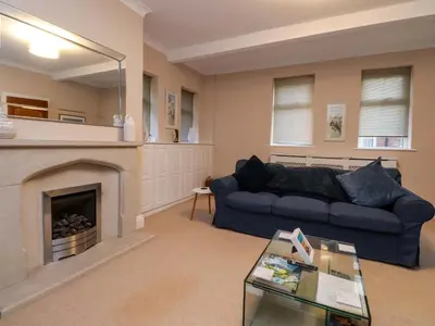 a living room with a blue couch and a fireplace at 6D Clifton Drive in Lytham St Annes