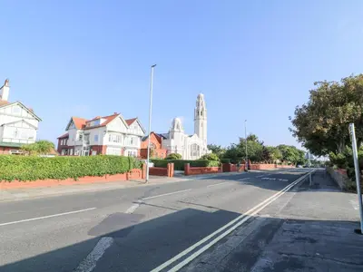 an empty street with houses and a church in the background at 6D Clifton Drive in Lytham St Annes
