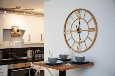 a large clock on a wall in a kitchen at Penthouse - Liverpool City Centre - NHS STAYS - Liverpool Royal Hospital in Liverpool