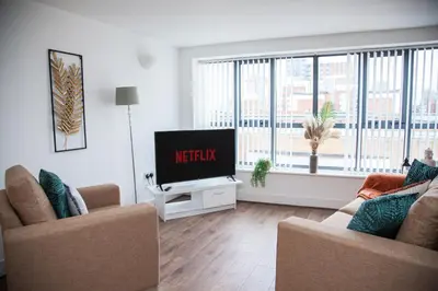a living room with a tv and two chairs at Penthouse - Liverpool City Centre - NHS STAYS - Liverpool Royal Hospital in Liverpool