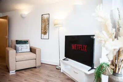 a living room with a flat screen tv and a chair at Penthouse - Liverpool City Centre - NHS STAYS - Liverpool Royal Hospital in Liverpool