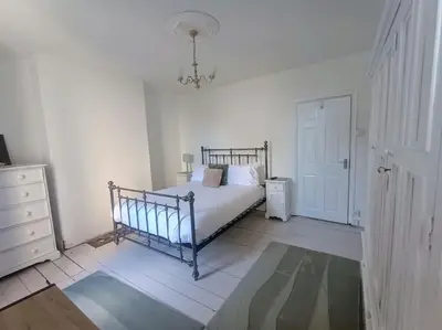 a bedroom with a bed and a dresser and a door at 4 Bed house Sea Views Benji's by the beach in Morecambe