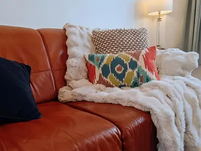 a brown leather couch with pillows and a blanket at 4 Bed house Sea Views Benji's by the beach in Morecambe