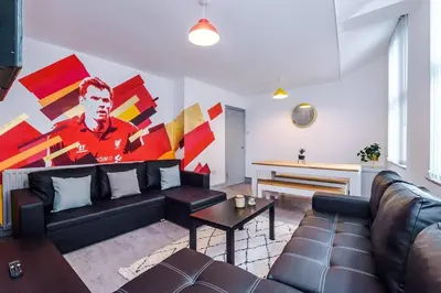 a living room with a couch and a large painting at 5 Sleeper LFC Themed Apartment in Liverpool