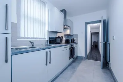a kitchen with white cabinets and a sink at LFC Themed Apartment in Liverpool