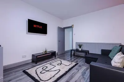 a living room with a couch and a clock on the wall at LFC Themed Apartment in Liverpool