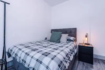 a bedroom with a bed with a black and white blanket at LFC Themed Apartment in Liverpool