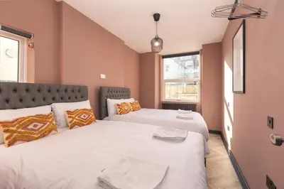 two beds in a room with pink walls at Ettie's in Blackpool