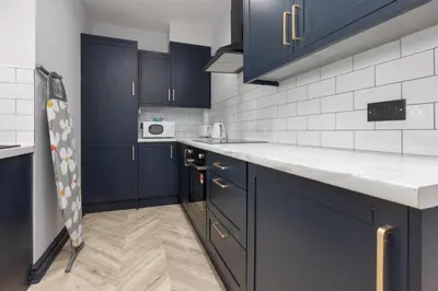 a kitchen with navy blue cabinets and white appliances at Ettie's in Blackpool