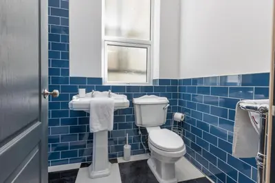 a blue tiled bathroom with a toilet and a sink at Ettie's in Blackpool