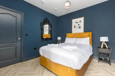 a bedroom with a large bed with blue walls at Ettie's in Blackpool