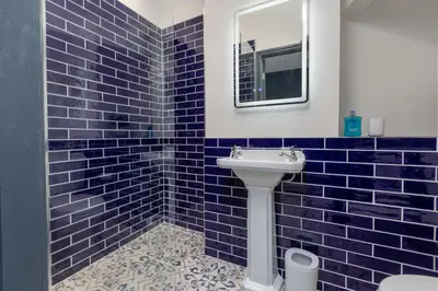 a blue tiled bathroom with a sink and a mirror at GiGi's in Blackpool