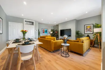 a living room with a table and yellow couches at Host & Stay - Upper Duke Street Apartment in Liverpool