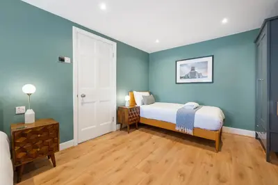 a bedroom with a bed with blue walls and wooden floors at Host & Stay - Upper Duke Street Apartment in Liverpool