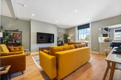 a living room with yellow couches and a kitchen at Host & Stay - Upper Duke Street Apartment in Liverpool